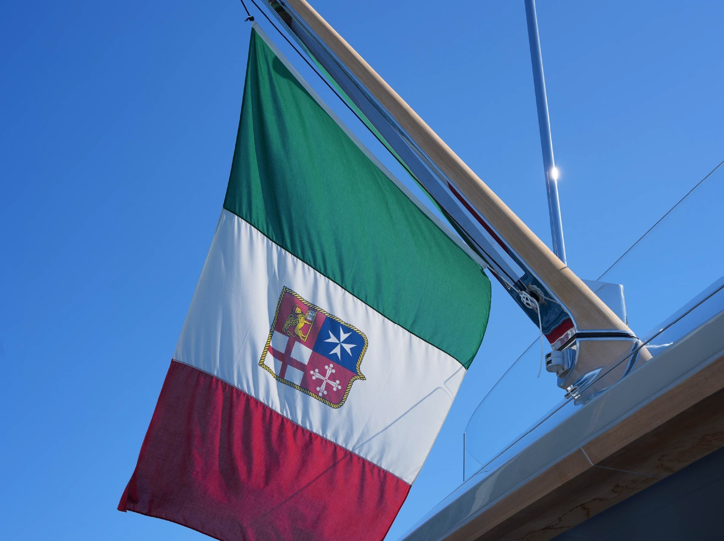 The Italian civil ensign flying from a yacht backstay against a clear sky