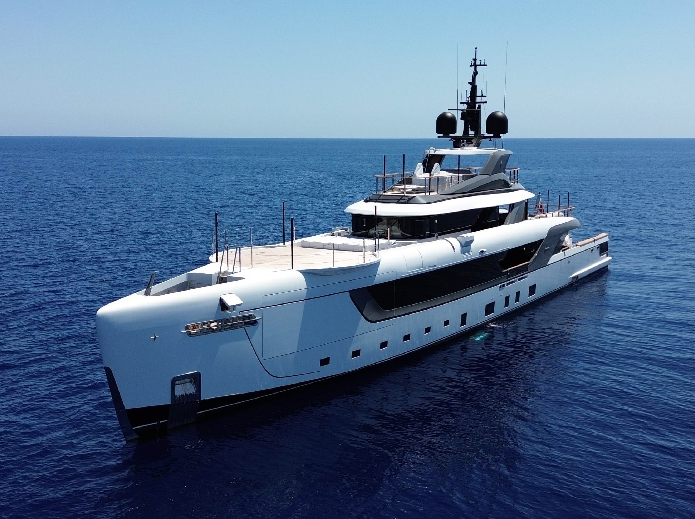 A white superyacht lying at anchor on deep blue open sea