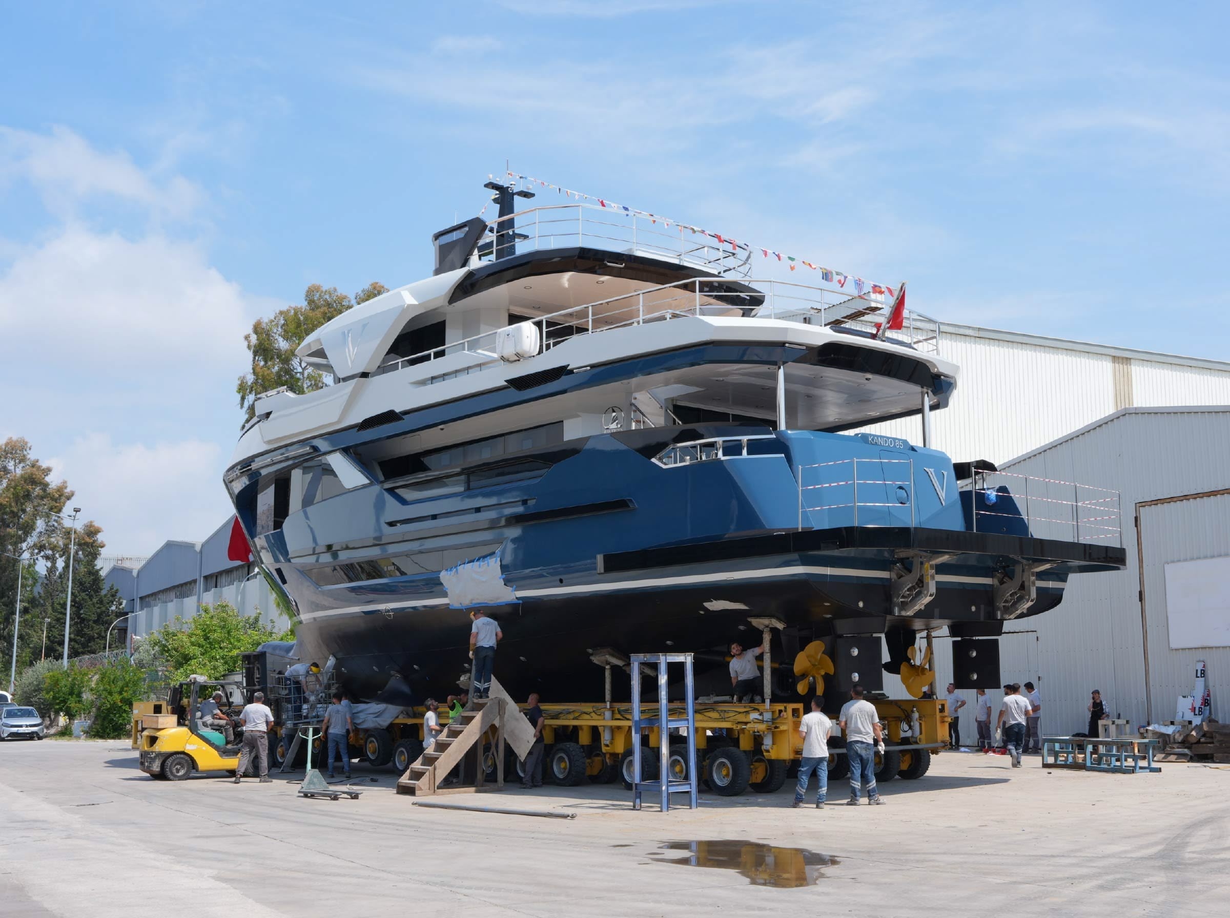 A motor yacht hauled out on her cradle in a shipyard with a team working alongside her