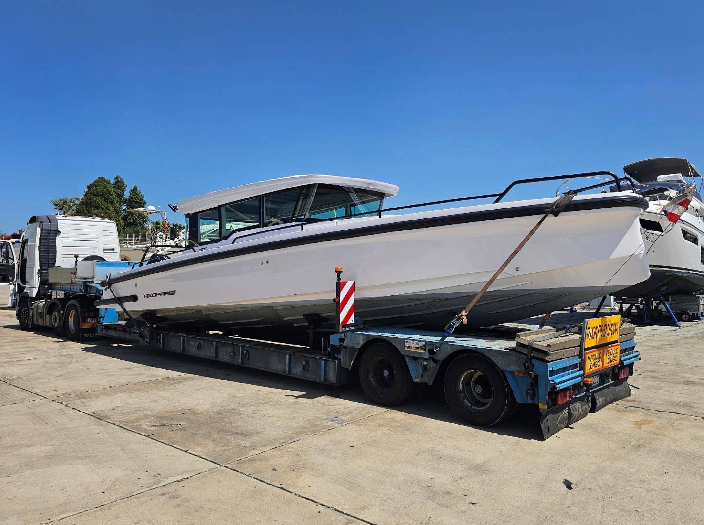 A motorboat strapped down on a low loader trailer on a quay, ready to be shipped
