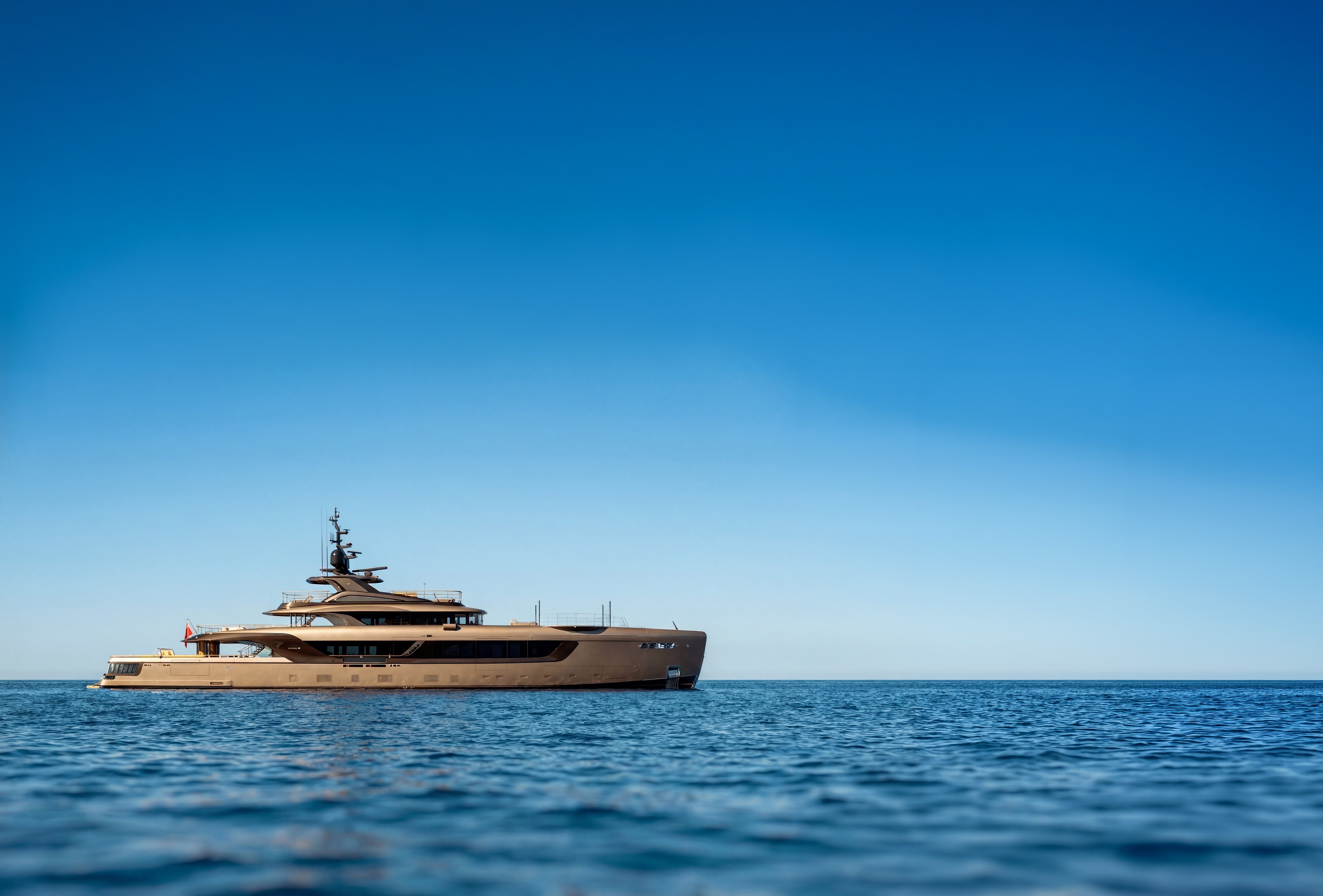 Superyacht lying at anchor on open water under a clear sky